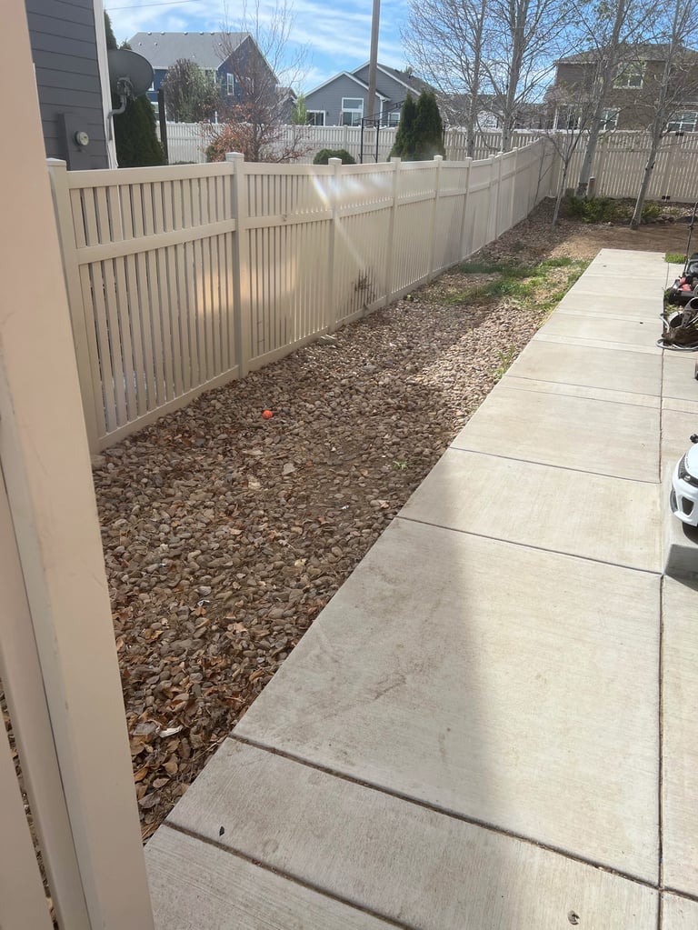 Backyard with white vinyl fence, concrete pathway, gravel ground, and mountain views in background